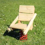 Foto der Federwippe Schaukelstuhl aus Robinienholz mit Lehne und Sitzfläche auf dicker, stabiler Schwingfeder Hintergrund: saftig-grüne Frühlingswiese mit Gänseblümchen