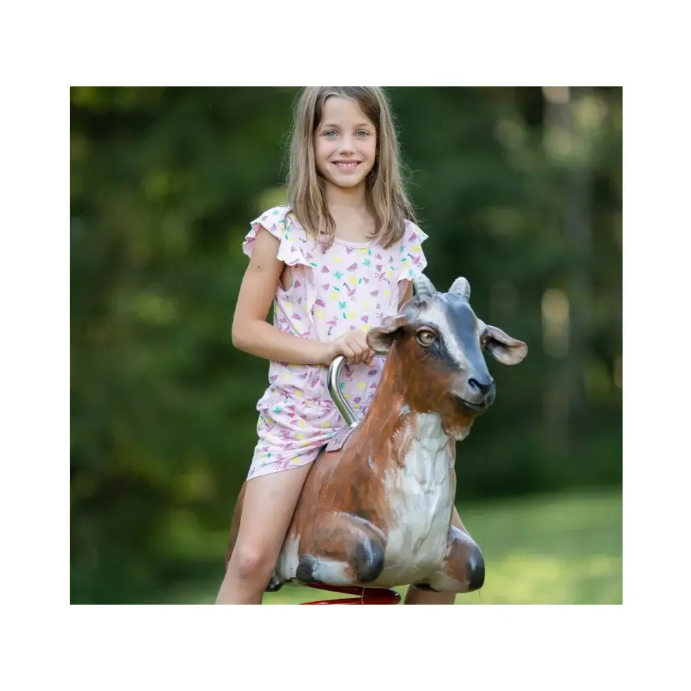 Foto: geschnitzes und bemaltes Federwipptier Ziege mit Edelstahlgriff. Mädchen sitzt auf seinem Rücken