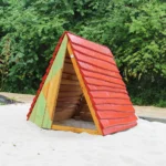 Spielhaus in Zeltform aus Robinienholz mit rot gedecktem Dach - auf Sandfläche im Außenbereich eines Spielplatzes.