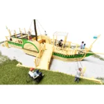 Spielgerät Dampfschiff Tristan in der Ansicht von schräg vorne, vom Pier aus. Mit Landungsbrücke für Rollstuhlfahrer, Balancierseil, Kletterwänden, Rutschstangen und Versteckmöglichkeiten im Rumpf